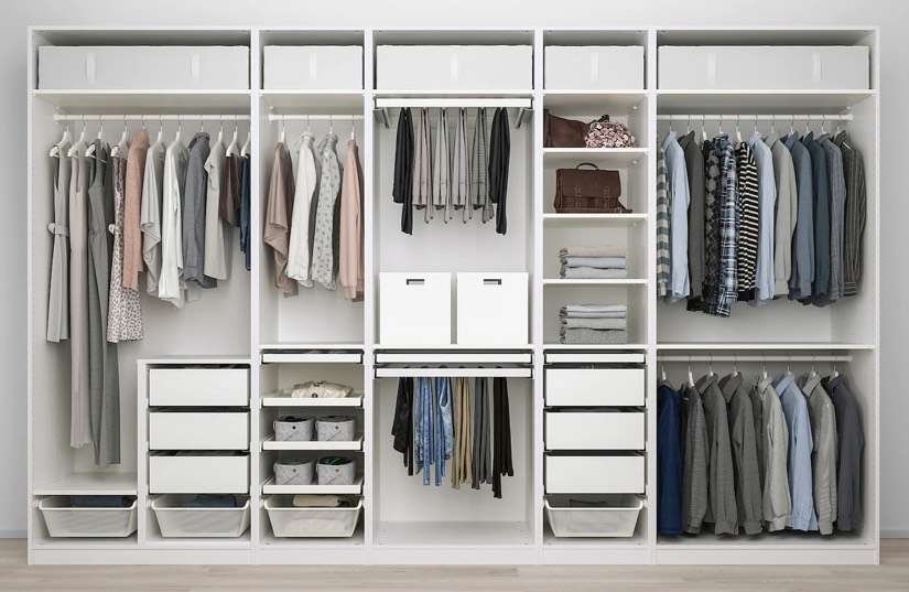 IKEA PAX wardrobe fully assembled with clothing, drawers, and shelves organized neatly.