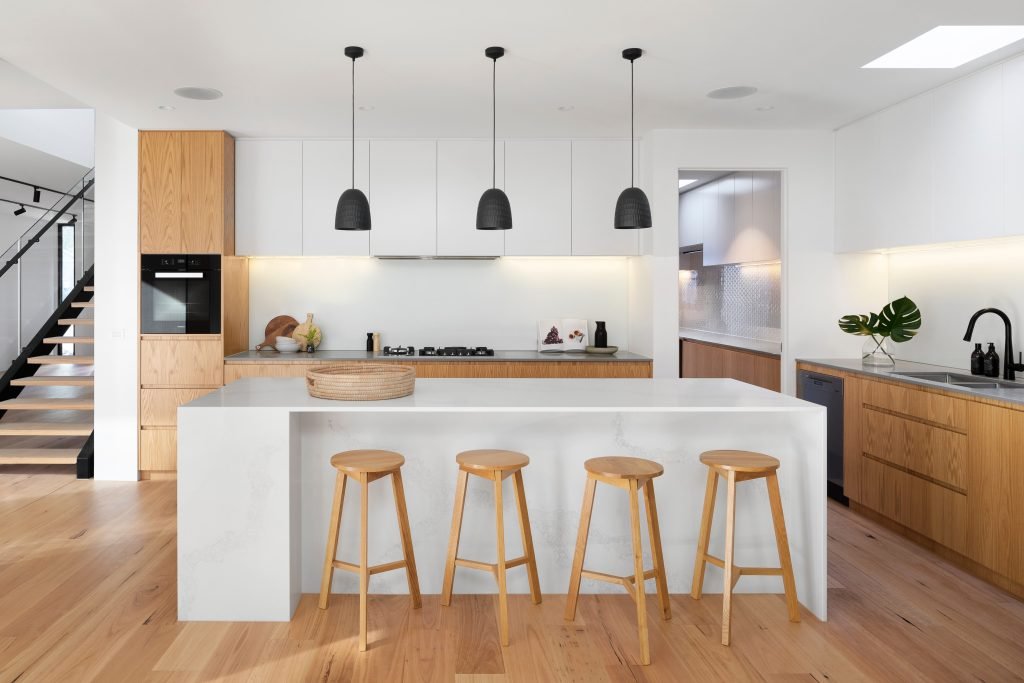 Modern IKEA Kitchen with Professional Assembly and Installation Modern kitchen with white countertops, wooden cabinets, and black pendant lights, showcasing professional IKEA kitchen assembly and installation.