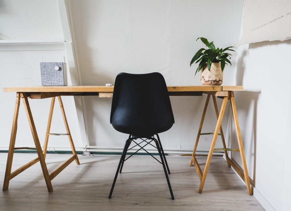 Professional Desk Assembly in Minimalist Workspace Minimalist workspace with a wooden desk and black chair, ideal for professional desk assembly and furniture assembly services.