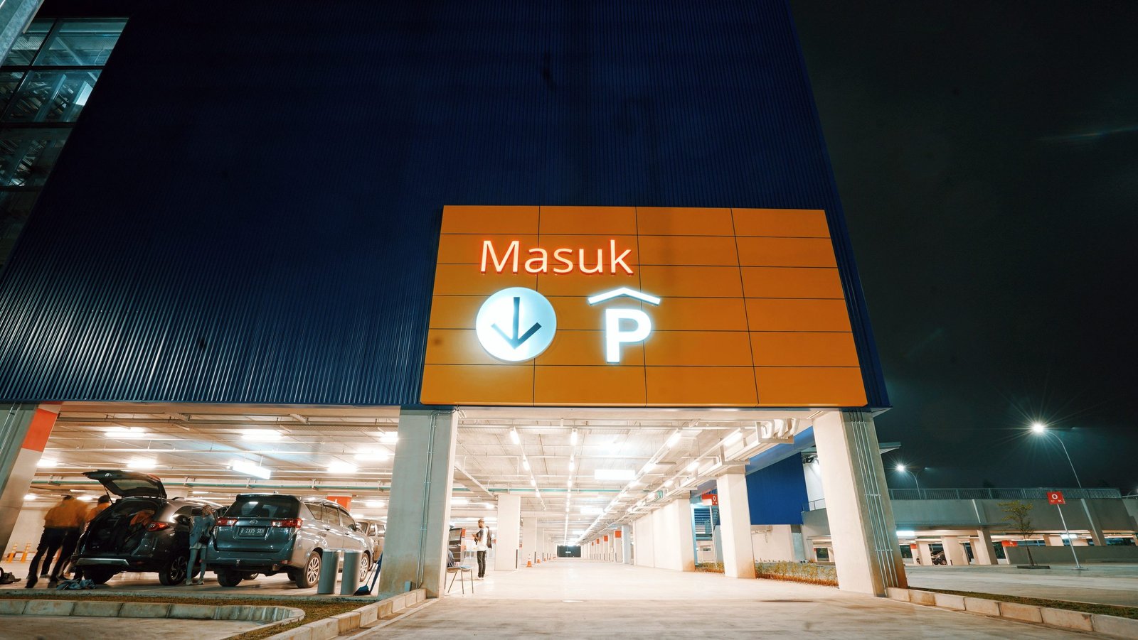 Nighttime IKEA Delivery and Alternative IKEA Delivery Entrance Parking garage entrance at night with an illuminated 'Masuk' sign, associated with IKEA delivery service and alternative IKEA delivery.
